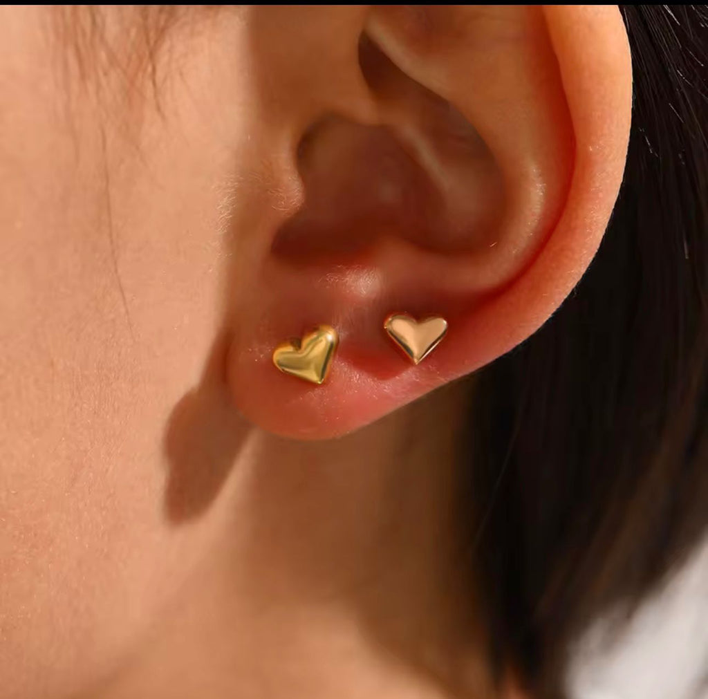 Inspiración de ear stack con dos aretes de corazón dorados en primer y segundo agujero.