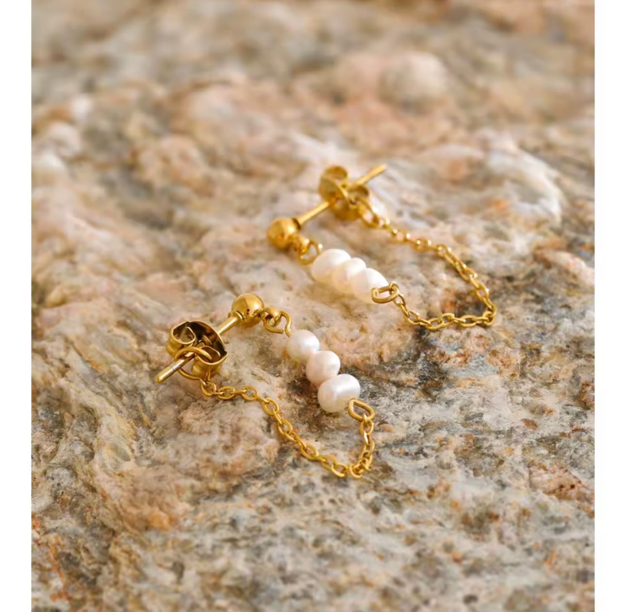 Par aretes perla natural cadena dorada sobre piedra